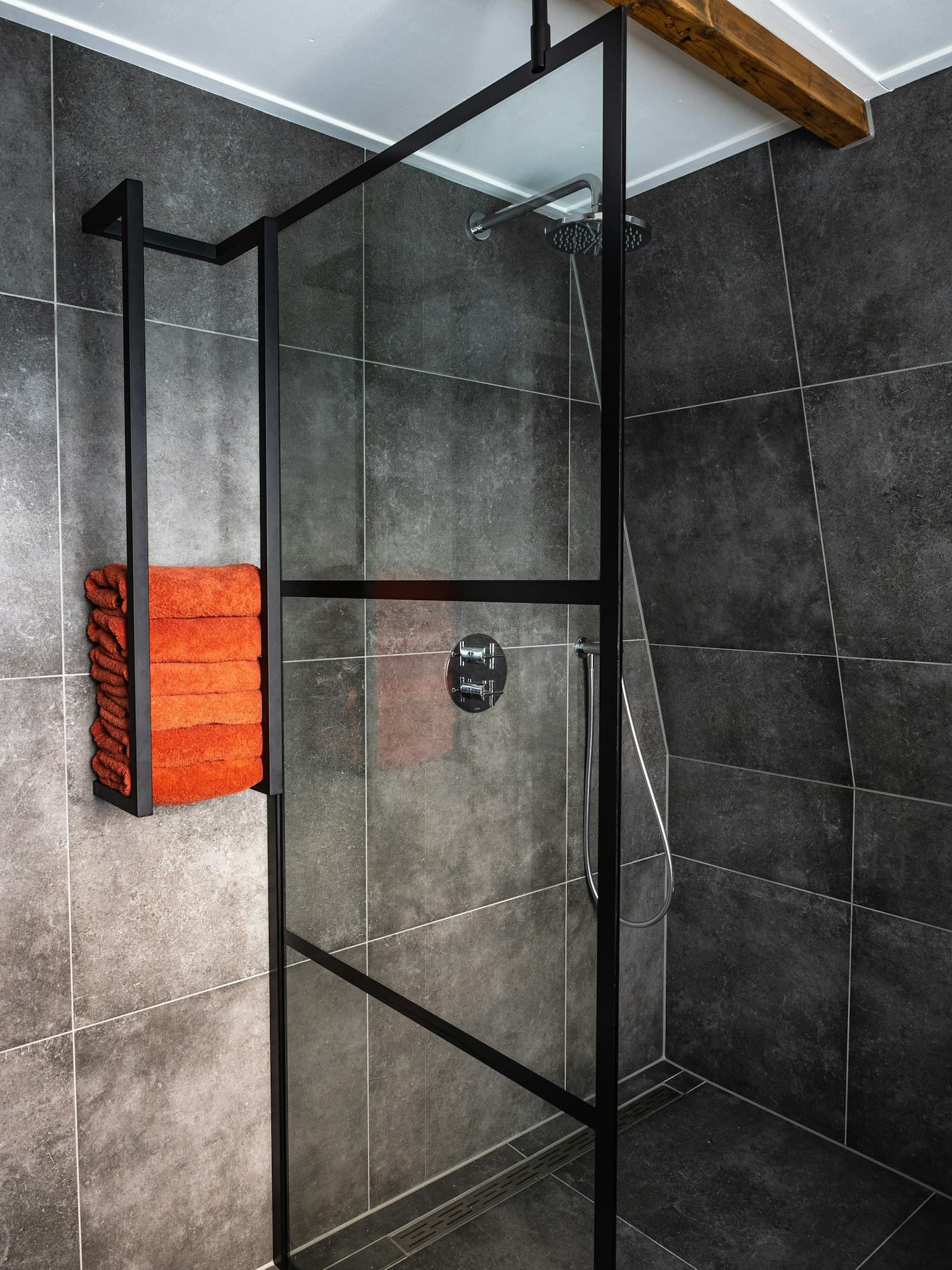 Begehbare Dusche mit dunklen Großformatfliesen und Glasabtrennung.