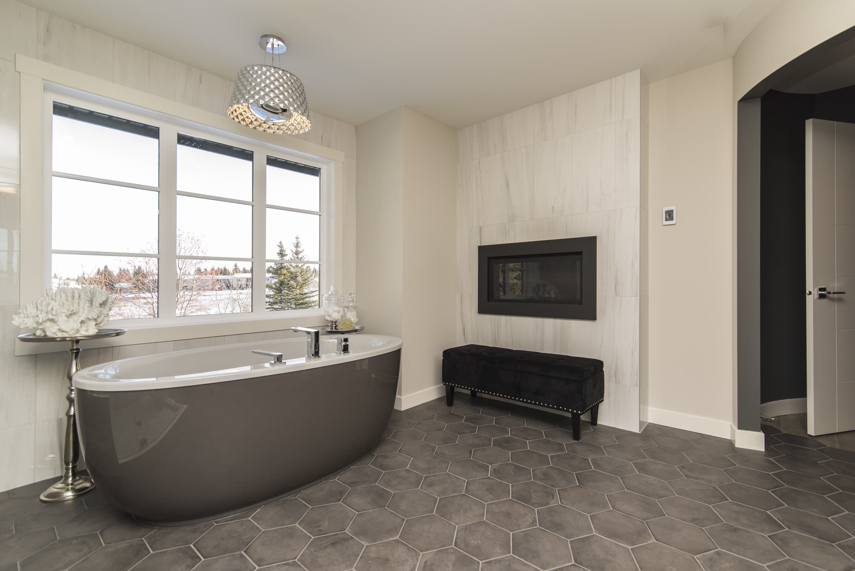 Hochwertiges, minimalistisches Badezimmer mit warmem Steinboden, Kupferarmaturen und freistehender Badewanne.